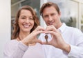 Closeup hands of happy married couple holding up new house keys with a heart shape hand gesture. Man and woman holding Royalty Free Stock Photo