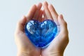 closeup of hands holding a blue glass heart against a white background Royalty Free Stock Photo