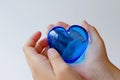 closeup of hands holding a blue glass heart against a white background Royalty Free Stock Photo