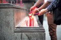 Closeup hands holding the bundle of incenses for lighting with candles in the sand tray