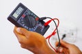Closeup hands holding multimeter with wires connected and numbers showing on display Royalty Free Stock Photo