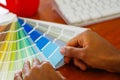 Closeup hands holding palette, colormap spread out in front of white computer keyboard, designer concept Royalty Free Stock Photo