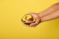 Closeup of hands holding two halves of ripe ready-to-eat avocado