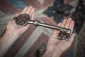 Closeup of hands holds old large huge massive metal key