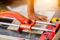 Hands of laborer using cutting tile machine at construction site with sun flare background