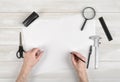 Closeup hands of man holding pencil and drawing on white paper in top view. Draftsman workplace equipped with ruler, pen Royalty Free Stock Photo