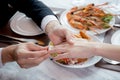 Closeup hands of man putting ring on finger of woman for marriage or engagement together with surprise at restaurant.