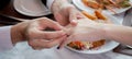 Closeup hands of man putting ring on finger of woman for marriage or engagement together with surprise at restaurant.