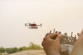 Closeup of hands operating drone transmitter, receiver controller, controller in focus while drone is in out of focus in Royalty Free Stock Photo