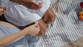 Closeup hands put rocks on woman legs summer picnic. Two lgbt girls having fun