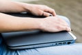 Closeup of hands resting on closed laptop.