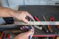 Closeup of hands with a ruler and a pencil measuring a mechanical piece of iron to be cut