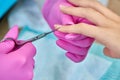 Closeup of hands of manicurist cutting cuticle with scissors female customer.