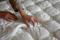 closeup of hands tucking in a white sheet on a mattress