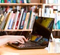 Closeup hands typing on notebook in library Royalty Free Stock Photo