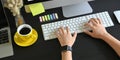 Closeup hands typing on wireless keyboard that putting on black wooden working desk. Royalty Free Stock Photo