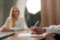 Closeup hands of unrecognizable female hand holding pen able to put name on paper contract, insurance policy, signing Royalty Free Stock Photo