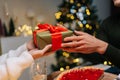 Closeup hands of unrecognizable happy young woman receiving Christmas gift from loving man at home on blurred background Royalty Free Stock Photo