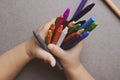 Closeup of child`s hands with colorful wax crayons pencils. learning concept. Flat lay