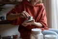 Closeup hands woman ceramist with saucer and hard sponge for buffing dishes after pottery kiln