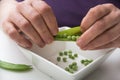 hands of woman peeling fresh organic peas on white table background Royalty Free Stock Photo