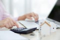 Closeup hands of woman sitting and planning and calculate expense and mortgage with calculator and home on desk.