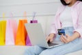 Closeup hands of woman sitting on sofa using laptop computer shopping online with credit card while paper bag. Royalty Free Stock Photo