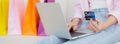 Closeup hands of woman sitting on sofa using laptop computer shopping online with credit card while paper bag. Royalty Free Stock Photo