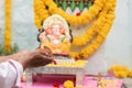 Closeup of Hands worshiping lord ganesh by offering aarti during vinayaka Chaturthi festival pooja or puja celebration at home in