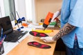 Closeup Hands of young man with tattoo in workshop dressed in blue uniform make individual orthopedic insoles. The instrument uses