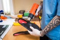 Closeup Hands of young man with tattoo in workshop dressed in blue uniform make individual orthopedic insoles. The instrument uses