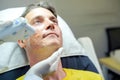 Closeup handsome man having color light therapy to stimulate facial skin by professional cosmetologist wellbeing Royalty Free Stock Photo