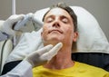 Closeup handsome man having color light therapy to stimulate facial skin Royalty Free Stock Photo