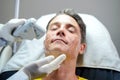 Closeup handsome man having color light therapy to stimulate facial skin by professional cosmetologist wellbeing Royalty Free Stock Photo