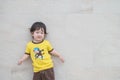 Closeup happy asian kid in dance motion with smile face on marble stone wall textured background with copy space Royalty Free Stock Photo