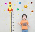 Closeup happy asian kid stand for measure height with cute cartoon at the marble stone wall textured background in growth of kid c Royalty Free Stock Photo