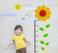 Closeup happy asian kid stand for measure height with cute cartoon sunflower at the marble stone wall textured background Royalty Free Stock Photo