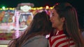 Closeup happy girls sharing secrets at funfair. Two friends gossiping laughing Royalty Free Stock Photo