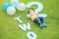 Closeup happy asian kid lie on grass floor in park textured background in 2 nd years anniversary concept Royalty Free Stock Photo