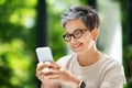 Closeup of happy mature woman using cell phone at workplace Royalty Free Stock Photo