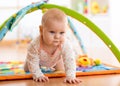 Closeup of happy seven months baby girl crawling on colorful playmat Royalty Free Stock Photo