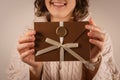 closeup happy woman holding Gift Certificate on beige background. handmade bronze envelope with ribbon