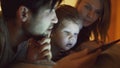 Closeup of Happy young family lying in bed at home while little boy learning to play digital tablet computer before