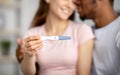 Closeup of happy young multiracial couple showing positive pregnancy test at camera, happy to have baby, selective focus