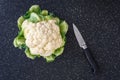 Closeup of head of cauliflower on a black cutting board, paring knife Royalty Free Stock Photo