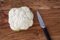 Closeup of head of cauliflower on a rustic wood cutting board, paring knife Royalty Free Stock Photo