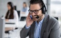 Closeup head shot of confident bearded call center operator talking and listening to customer while using headset with microphone Royalty Free Stock Photo