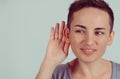 Closeup head shot macro face young nosy woman hand to ear gesture carefully intently secretly listening juicy gossip conversation