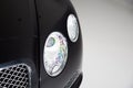 Closeup of the headlight of a black luxury car under the lights against a grey background Royalty Free Stock Photo