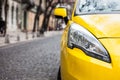 Closeup headlight of modern sport yellow car. Car exterior details over city background.